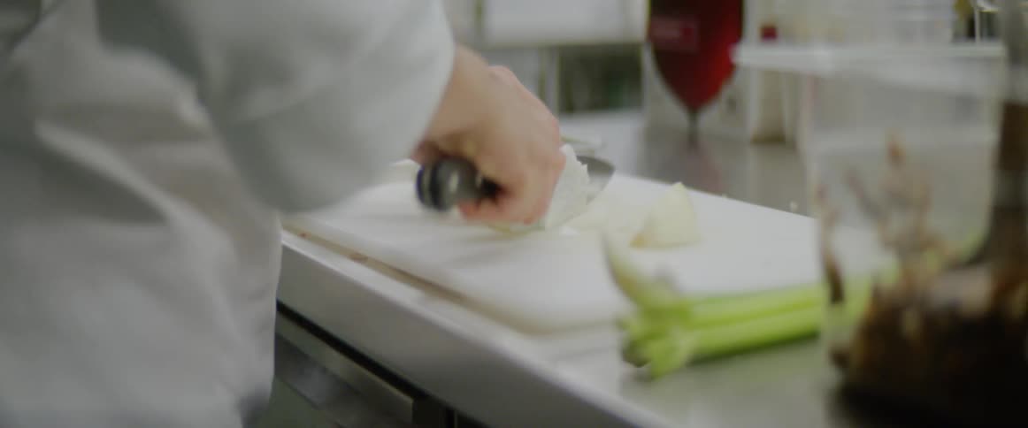 A chef cuts an onion in the kitchen of a restaurant