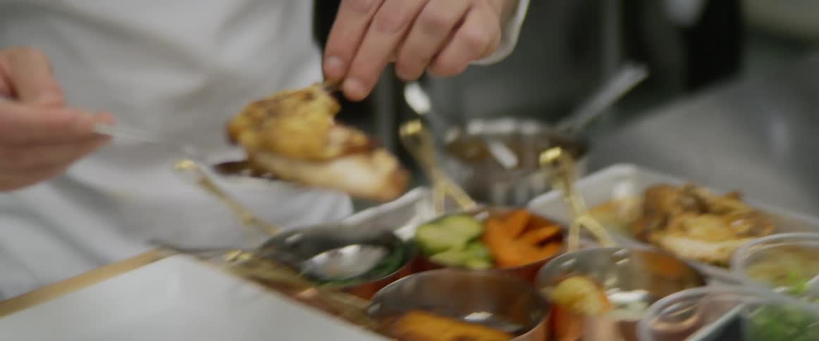 A chef is arranging a dish from a tray