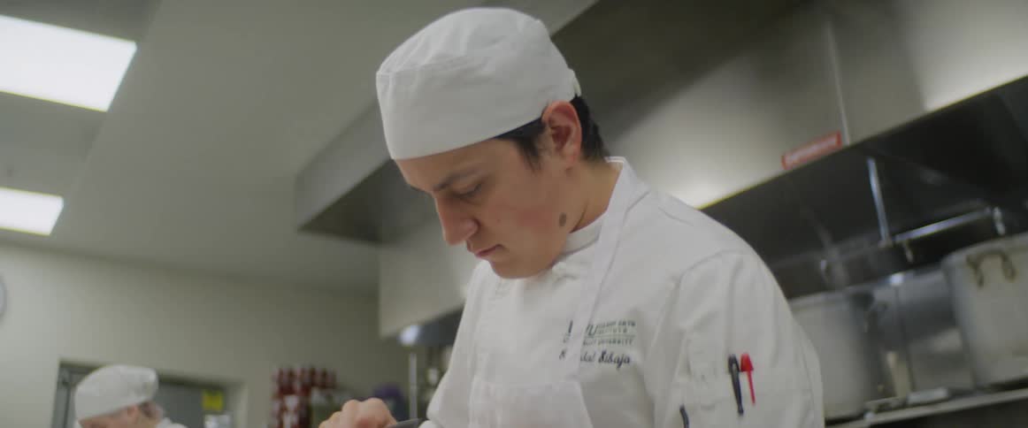 A chef peels a carrot in a kitchen