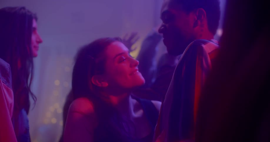 Couple dancing at crowded party under changing lights