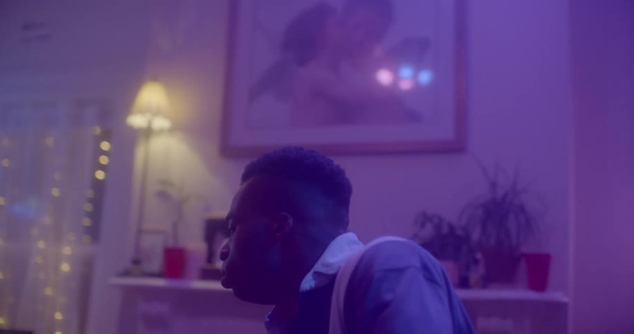 Man dances near fireplaces in purple lit room