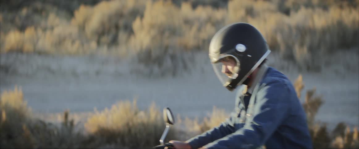 Man wearing a helmet rides a motorcycle on the dirt road