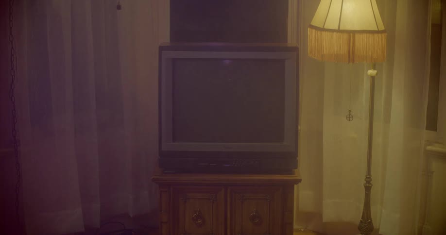 An old tv sits near a floor lamp