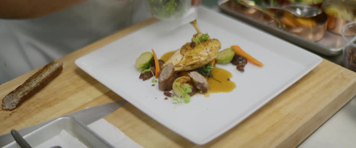 A chef is preparing food on a plate