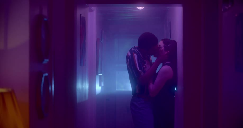A man and a woman standing in a hallway hugging and kissing