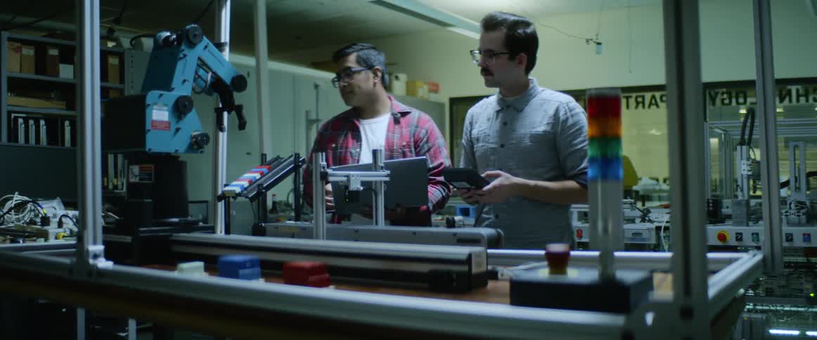 Two men control a robot in a shop