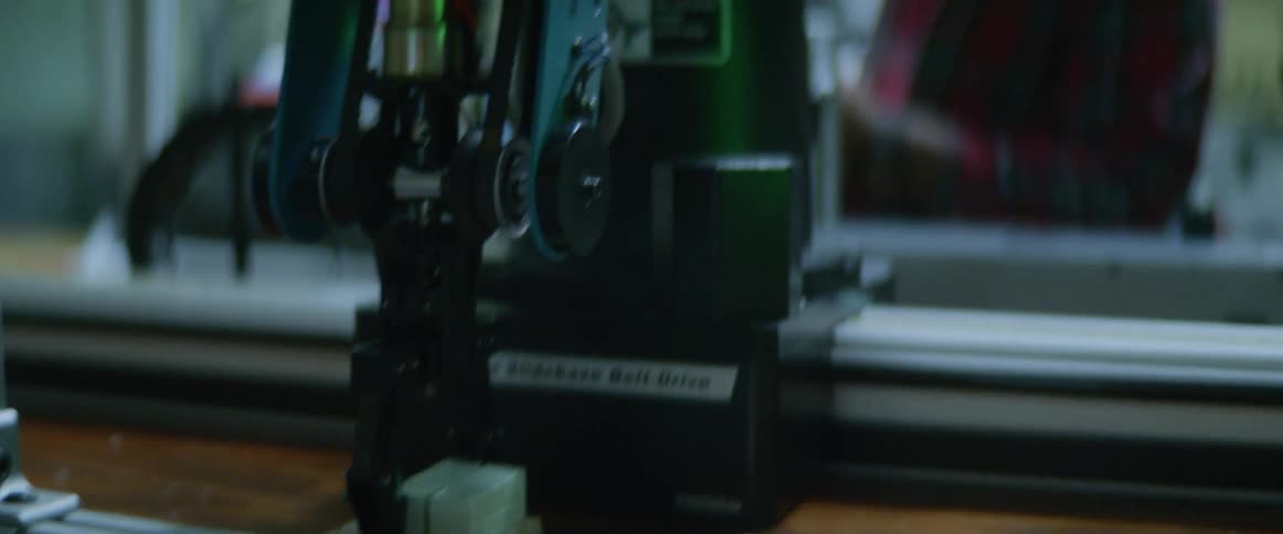 Two men happily watch as a robotic machine places items down