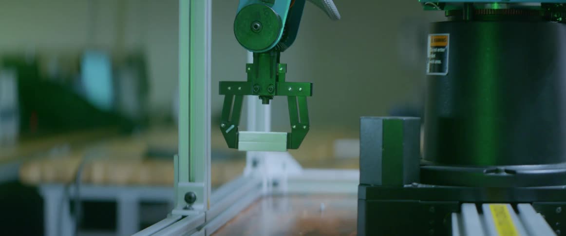 A robot arm putting an object on a small wooden pallet