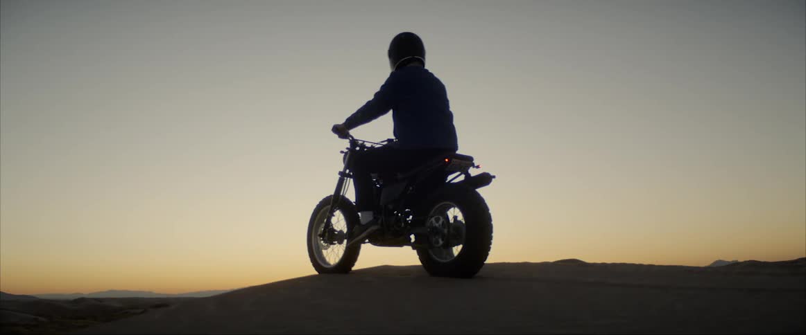 A man is sitting on a motorcycle in a rural area