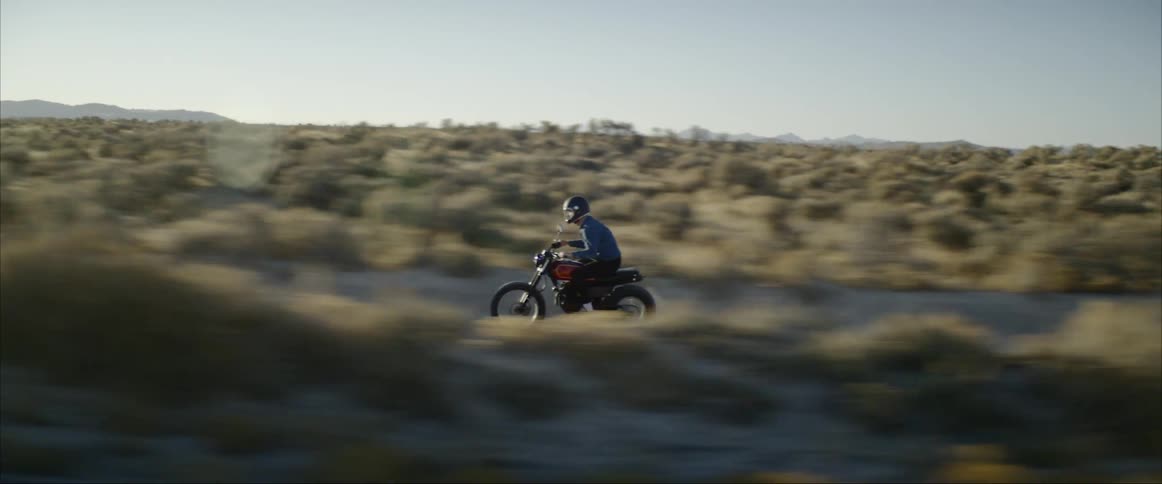 A person rides a motorcycle through the desert