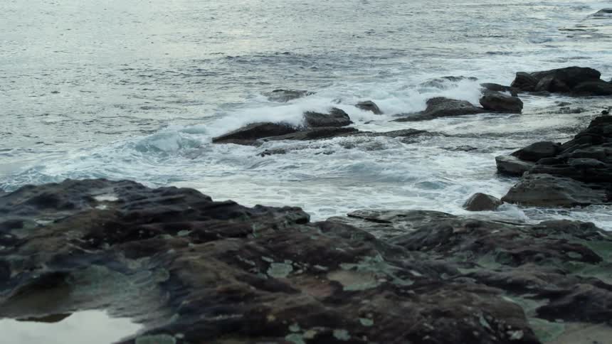 Ocean waves crashing over rocks on a beach