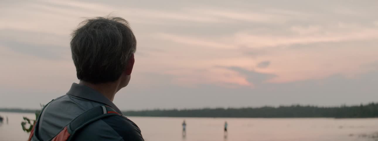 A man wearing a backpack looking out over the lake