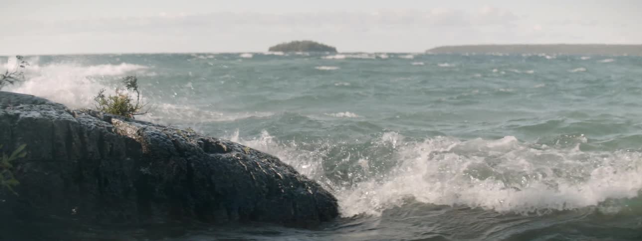 Waves slap across a large rock