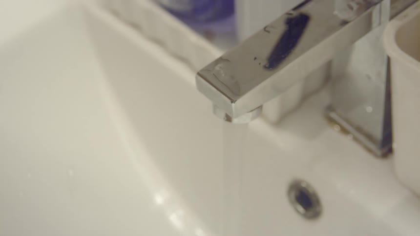 A person washes their hands at a sink