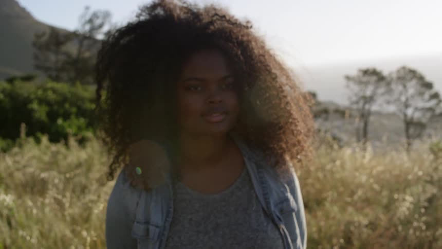 A girl with curly hair walks in a field