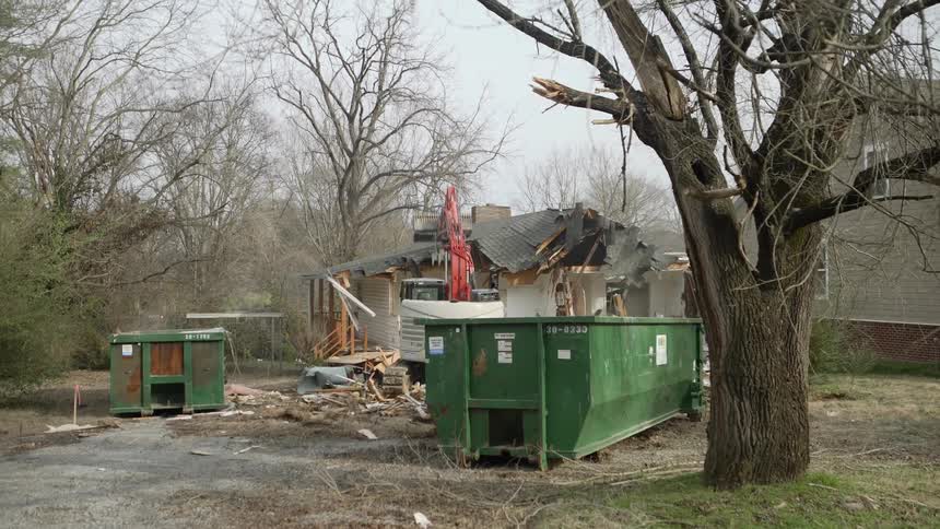 A crane crashes the roof of a house