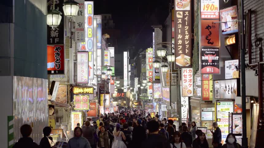 People walk the city streets at night in Tokyo