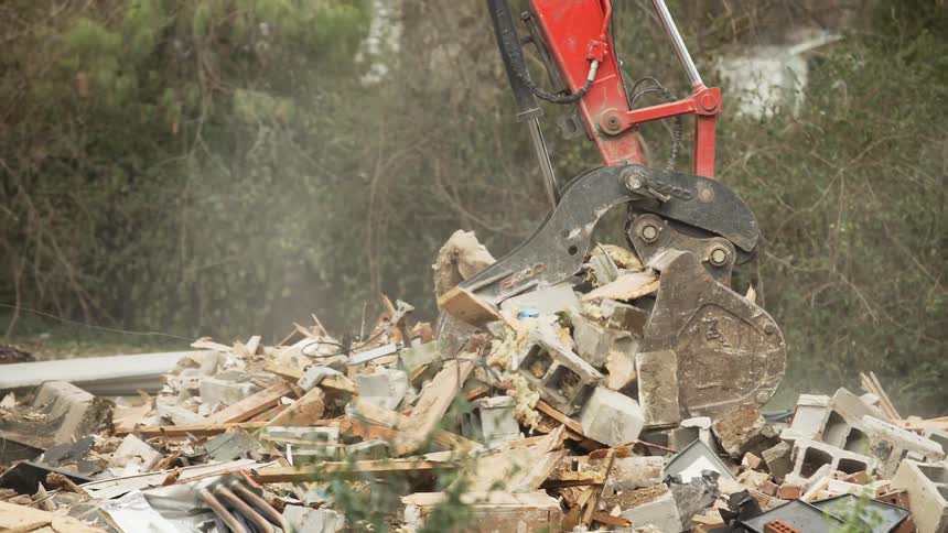 Excavator loads dump truck with debris