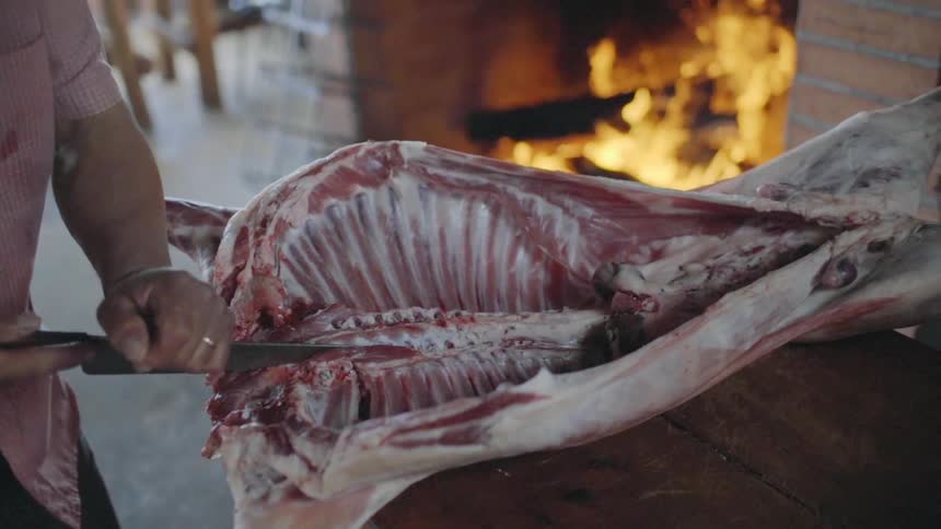 A man slices in to a big slab of raw meat