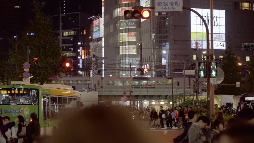 Hundreds of people cross a busy city intersection in Tokyo