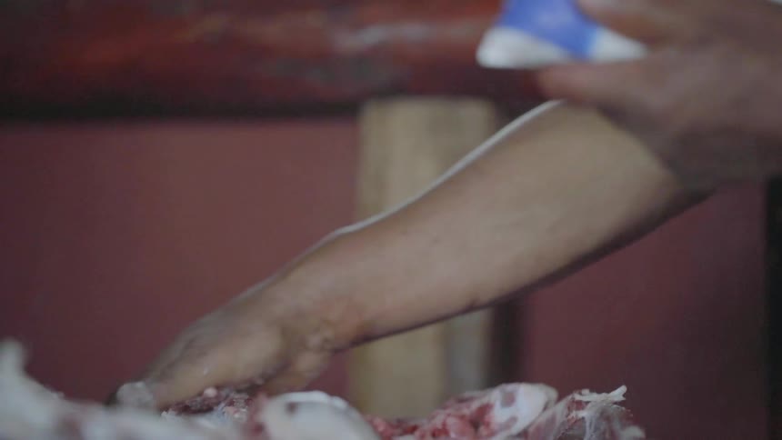 A person spreads powder over a pile of raw meat