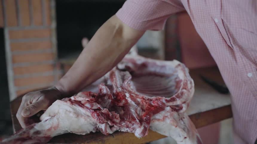 A man pulls apart raw meat