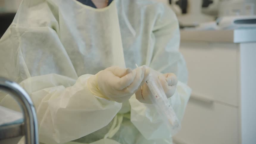 Nurse in surgical gown removing an item from sterilized bag