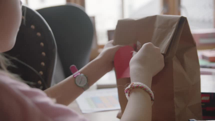 Woman wraps a package and sticks a heart shape card on it