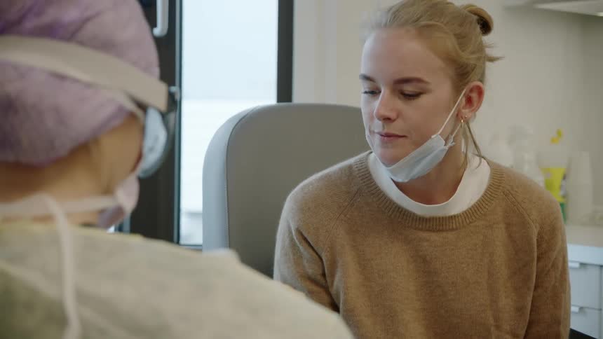 Medical personnel wearing protective gear takes mouth sample from patient