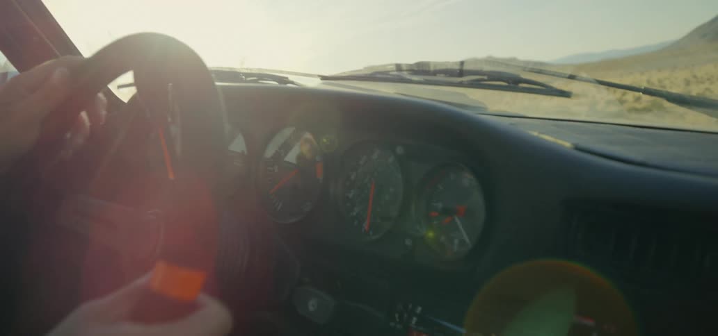 A person steers their vehicle over a bumpy dirt road that spans a wide open grassy plain