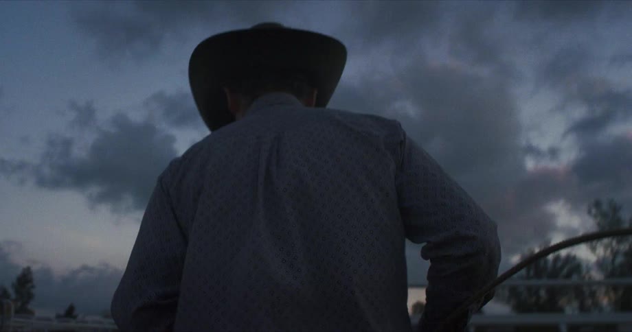 A cowboy walks over to a fence