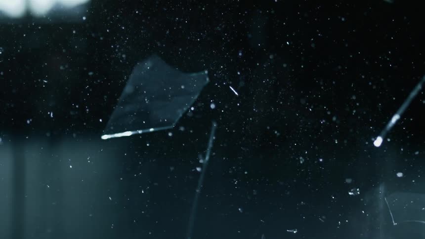 Glass fragments glitter as they fall through the air