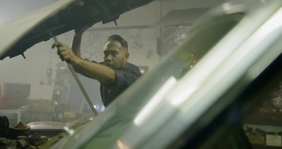 Mechanic working on vintage car inside workshop
