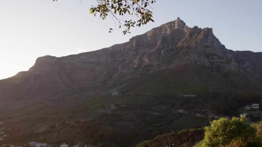 A breeze blows a branch as the sun shines on mountain tops and the valley below