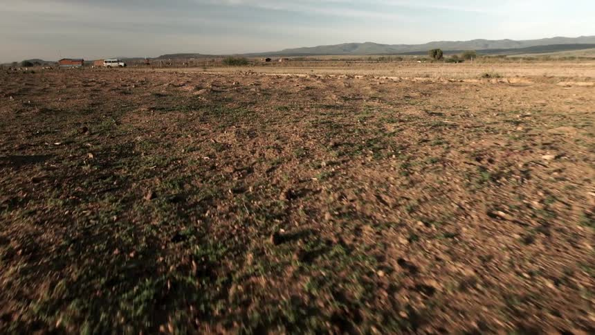 A field of grass and dirt leads to a dusty road