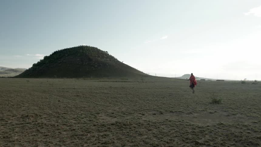 A shawled man walks alone in the wilderness