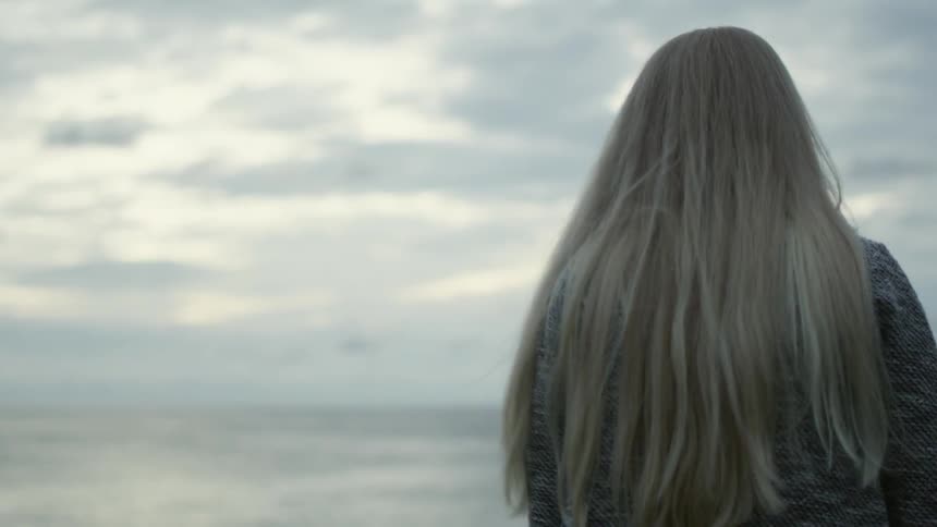 A woman walks towards the water