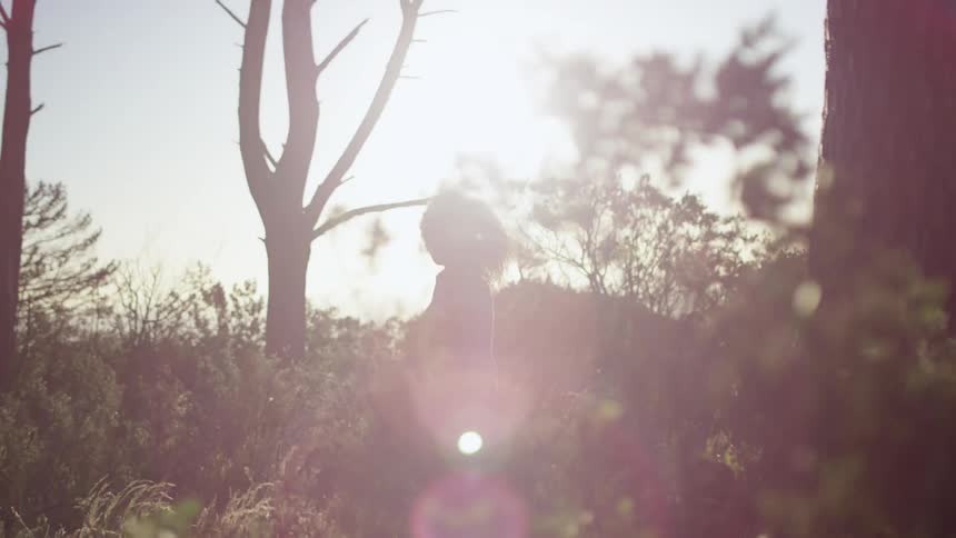 A woman runs through a grassy area on a sunny day