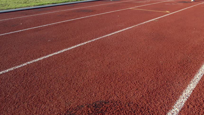 A person runs down a red track