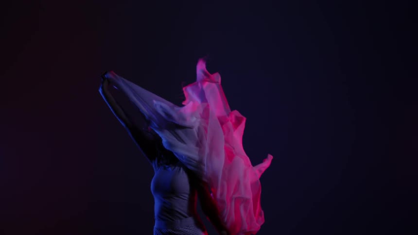 A woman dances with a piece of fabric blowing in the wind