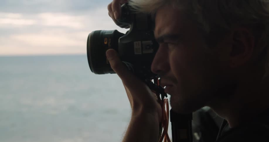 Man takes a photograph of the ocean with a camera