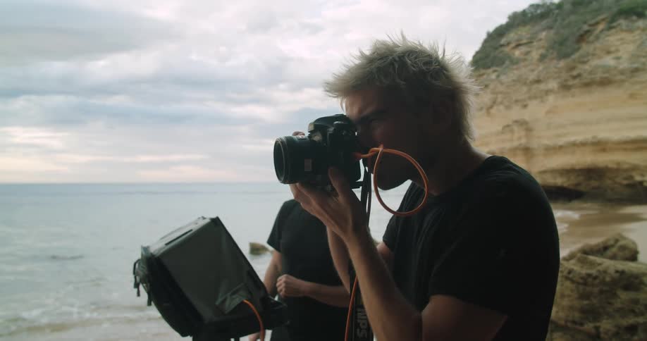 A professional photographer takes photos on the shore of the beach