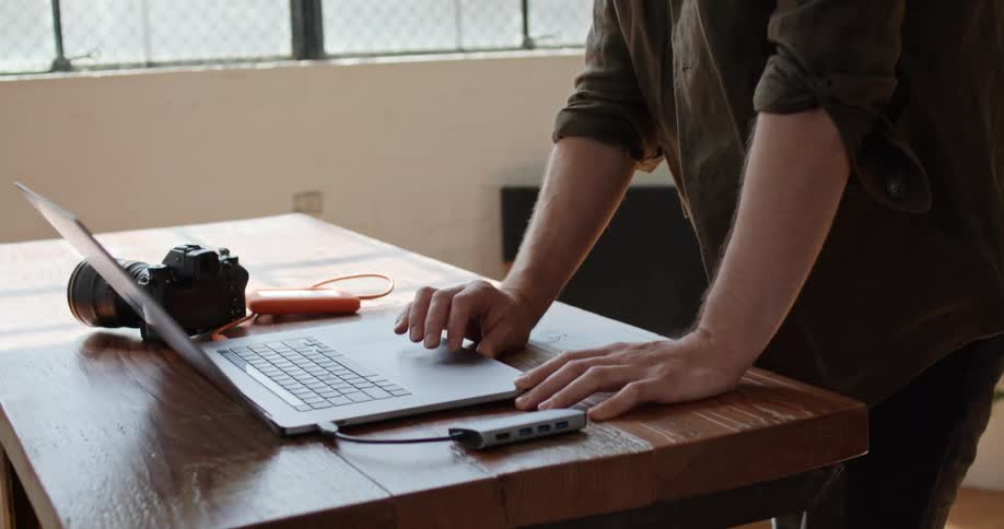 Man standing in front of the desk uses laptop indoors