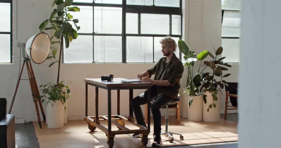 A man sits down at his desk and opens his laptop
