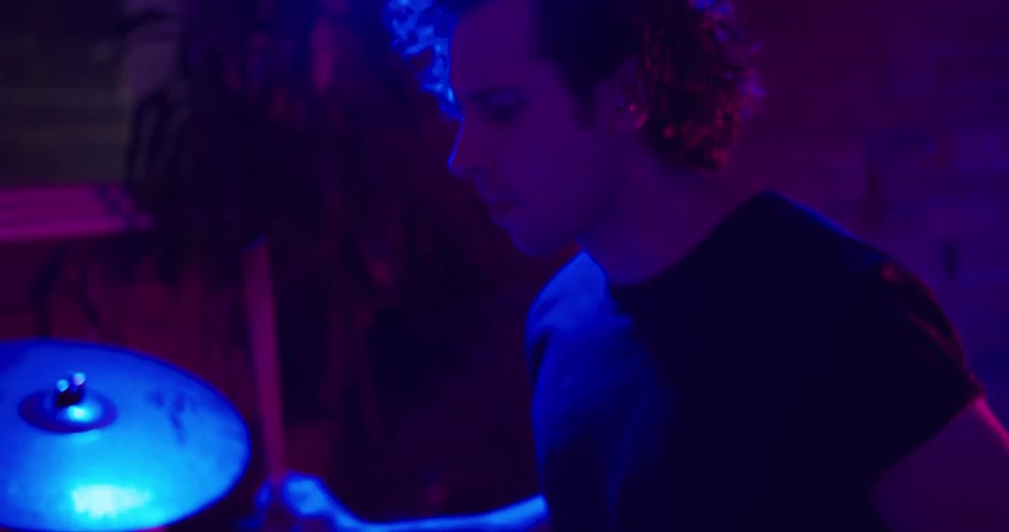 Drummer plays under violet tinted lights