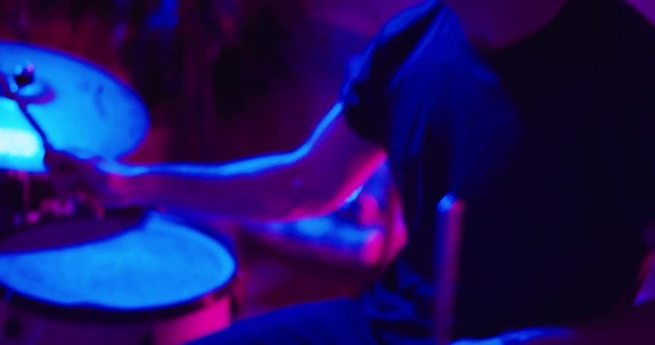 Drummer plays drums in the uv illuminated studio