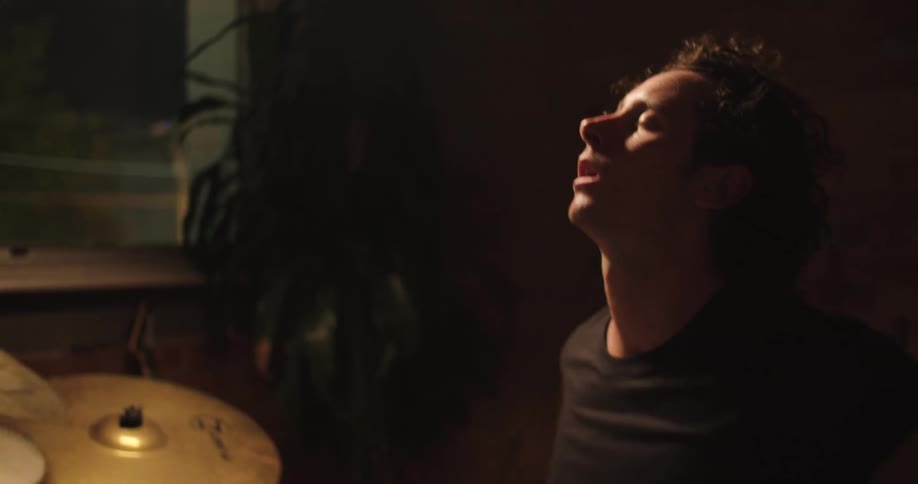 A man dramatically finishing a drumming session