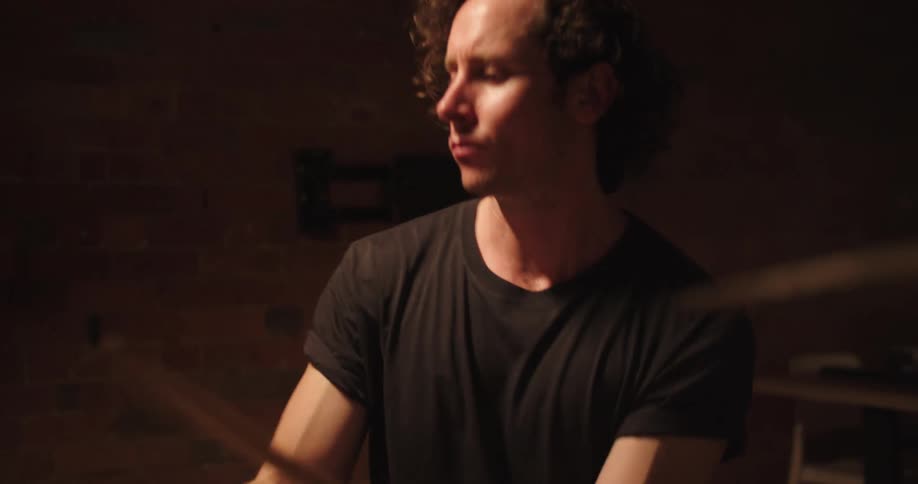Man with curly hair plays the drums