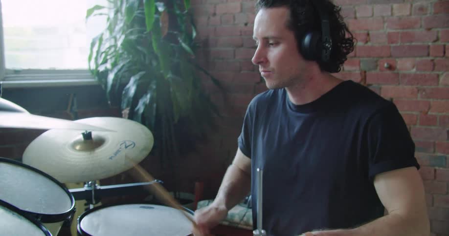 A man wears headphones while drumming