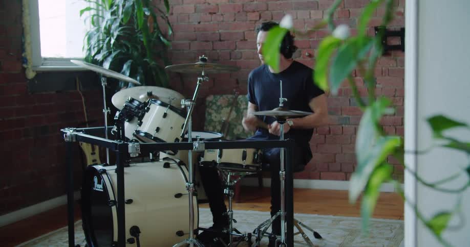 A man playing the drums indoors during the day
